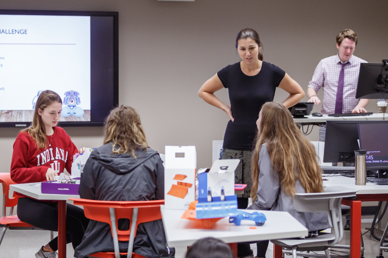 An instructor speaks to students seated at a table