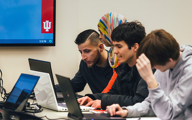 Students on laptops with instructor observing in IU Indianapolis classroom